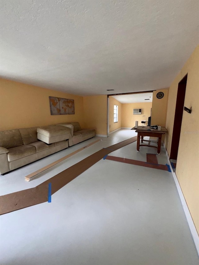 unfurnished living room with a textured ceiling and baseboards