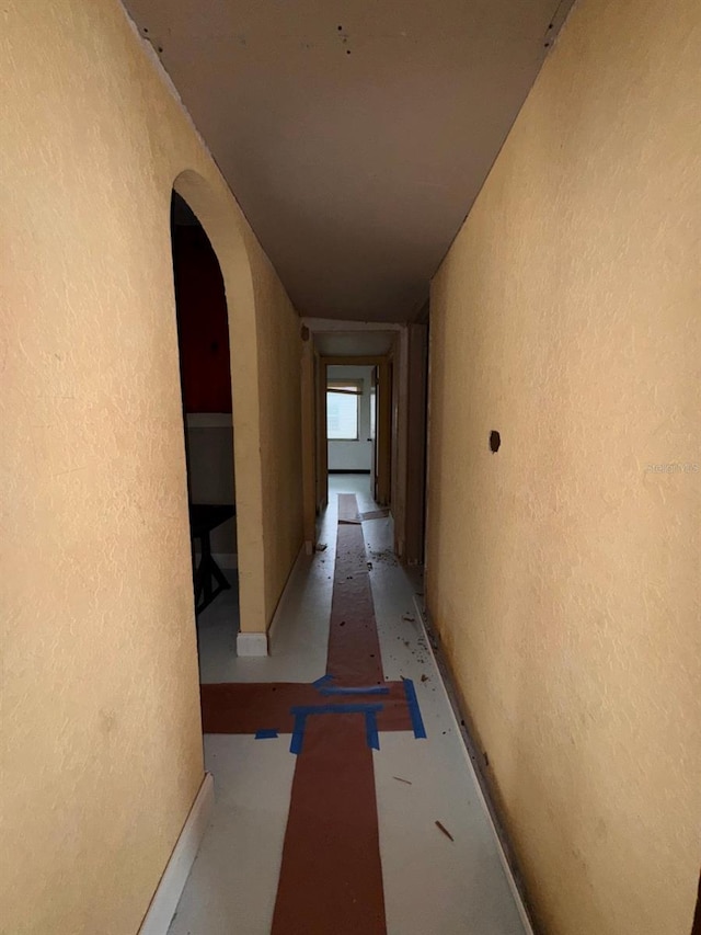 hall featuring arched walkways and a textured wall