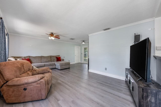 living room with ornamental molding, visible vents, a ceiling fan, and wood finished floors