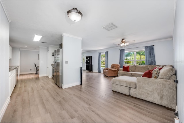 living room with baseboards, ornamental molding, a ceiling fan, light wood-style floors, and visible vents