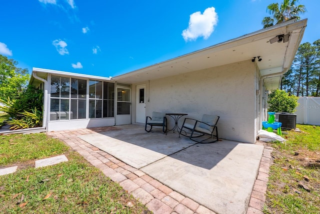 back of property with a sunroom, a patio area, fence, cooling unit, and stucco siding