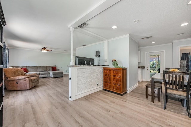 living area with visible vents, light wood-type flooring, crown molding, and a ceiling fan