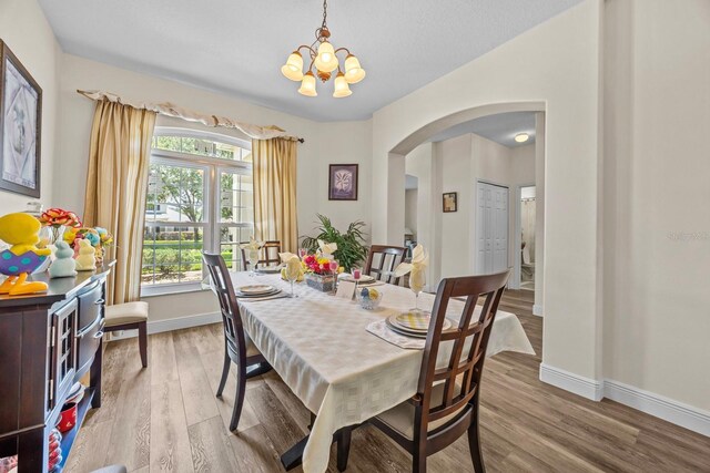 235 Largovista Dr, Oakland, FL 34787 - dining room featuring a chandelier, arched walkways, wood finished floors, and baseboards