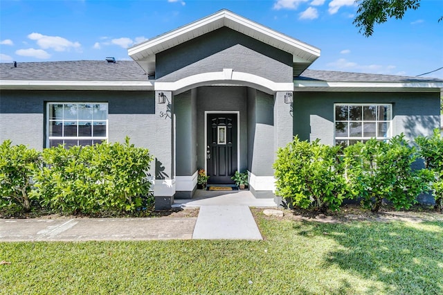 37 Lindsay Dr, Palm Coast, FL 32137 - entrance to property with roof with shingles, stucco siding, and a lawn