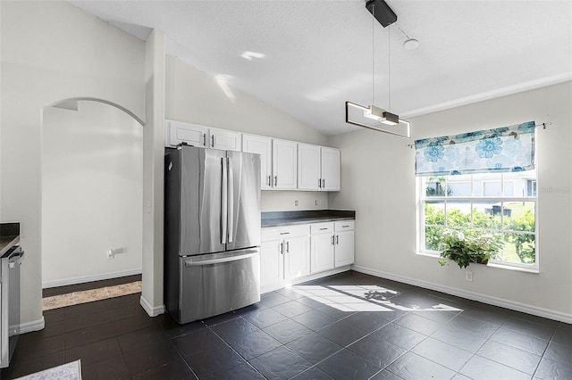 37 Lindsay Dr, Palm Coast, FL 32137 - kitchen featuring freestanding refrigerator, arched walkways, white cabinets, vaulted ceiling, and dark countertops