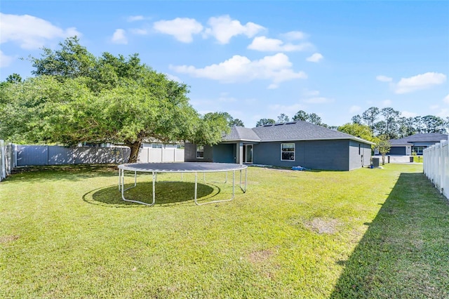 37 Lindsay Dr, Palm Coast, FL 32137 - back of property featuring a trampoline, a yard, a fenced backyard, and stucco siding