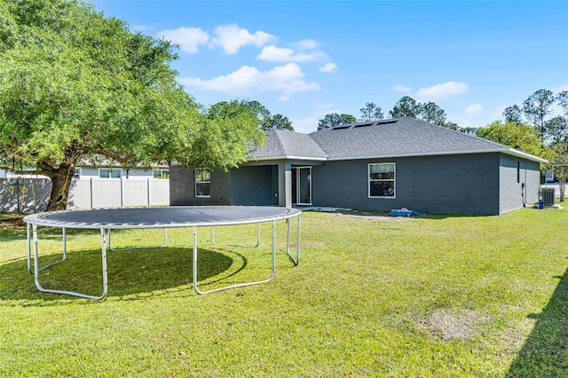 37 Lindsay Dr, Palm Coast, FL 32137 - rear view of house featuring central AC, a yard, stucco siding, fence, and a trampoline