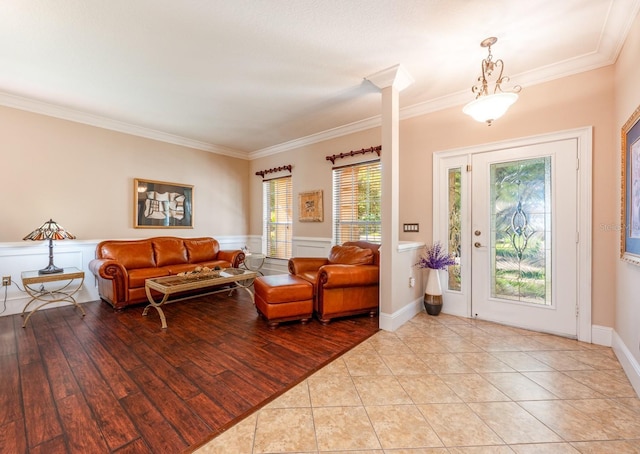 living room featuring crown molding, wainscoting, and light wood-style floors
