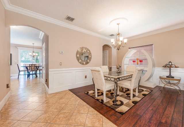 dining space with arched walkways, an inviting chandelier, ornamental molding, and visible vents