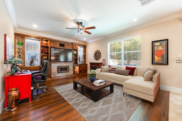 living area featuring baseboards, ornamental molding, a ceiling fan, visible vents, and wood finished floors