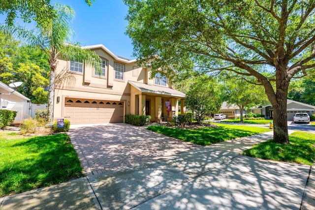 traditional-style home featuring a garage, stucco siding, a front yard, fence, and driveway