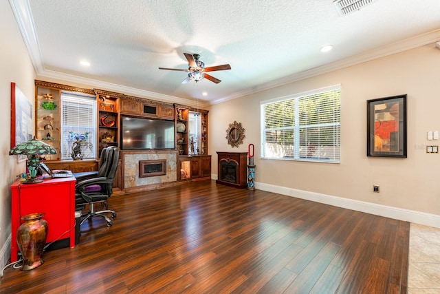 home office featuring a fireplace, a textured ceiling, crown molding, ceiling fan, and wood finished floors
