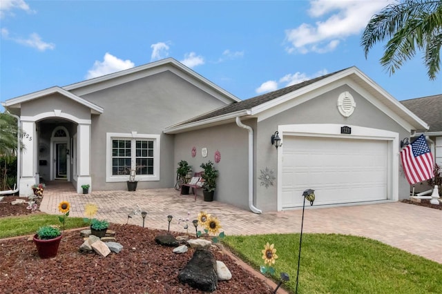 single story home with a garage, stucco siding, and decorative driveway