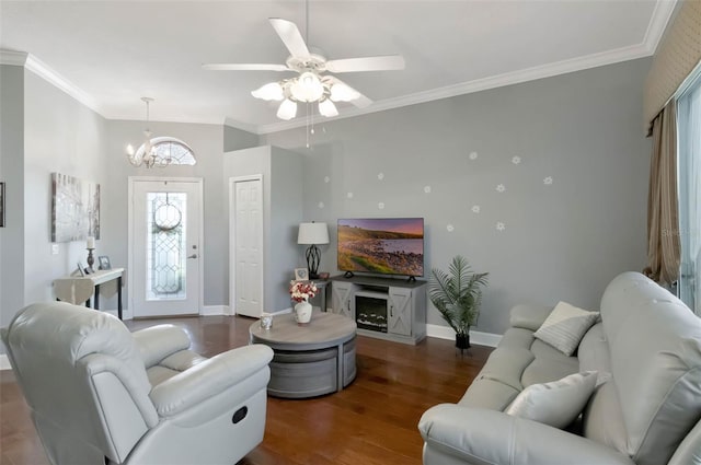 living room featuring ceiling fan with notable chandelier, baseboards, ornamental molding, and wood finished floors