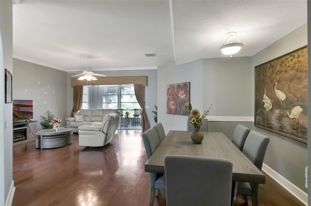 dining space featuring ornamental molding, a ceiling fan, visible vents, wood finished floors, and baseboards