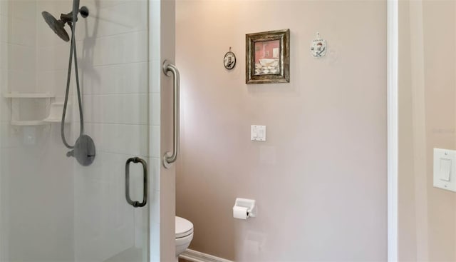full bathroom with toilet, a stall shower, and baseboards