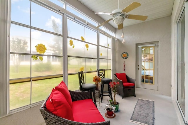 sunroom / solarium with a textured wall, concrete flooring, and a ceiling fan