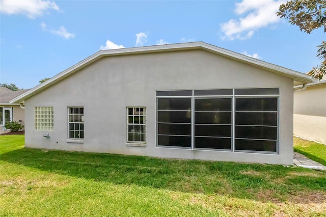 rear view of house featuring stucco siding and a lawn