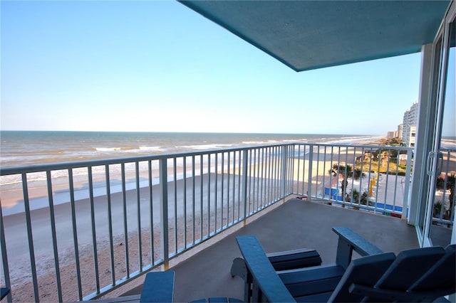 balcony with a water view and a view of the beach