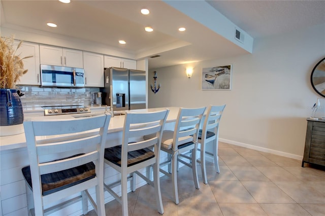 5203 S Atlantic Ave Unit 416B, New Smyrna Beach, FL 32169 - kitchen with appliances with stainless steel finishes, white cabinets, baseboards, decorative backsplash, and light countertops