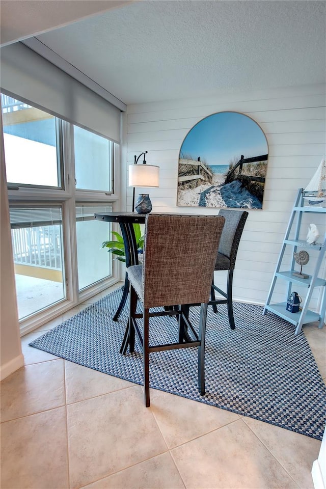 5203 S Atlantic Ave Unit 416B, New Smyrna Beach, FL 32169 - dining space featuring wood walls, a textured ceiling, and tile patterned floors