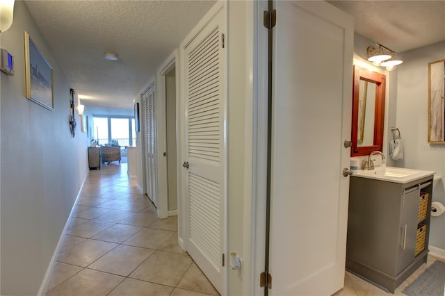 5203 S Atlantic Ave Unit 416B, New Smyrna Beach, FL 32169 - corridor featuring a sink, a textured ceiling, baseboards, and light tile patterned floors