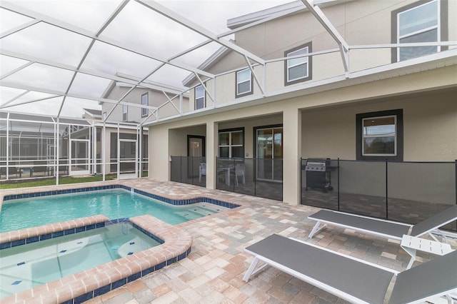 view of pool featuring a patio area, a pool with connected hot tub, and glass enclosure