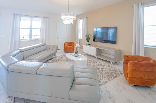 living room featuring marble finish floor, baseboards, and an inviting chandelier