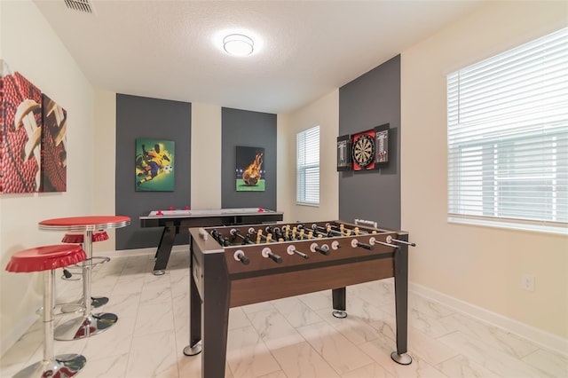 rec room featuring a healthy amount of sunlight, marble finish floor, baseboards, and visible vents