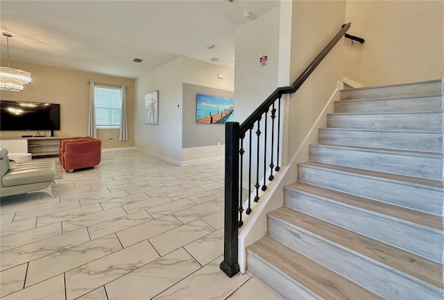 stairs featuring marble finish floor, baseboards, visible vents, and a notable chandelier