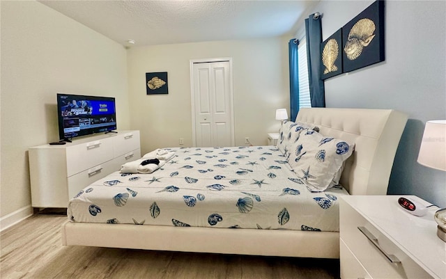 bedroom with a closet, baseboards, and wood finished floors