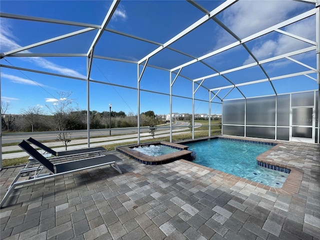 view of pool featuring a patio area, a pool with connected hot tub, and glass enclosure
