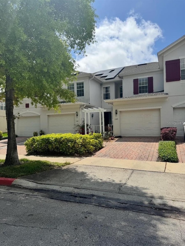 view of front of house with decorative driveway, an attached garage, and stucco siding