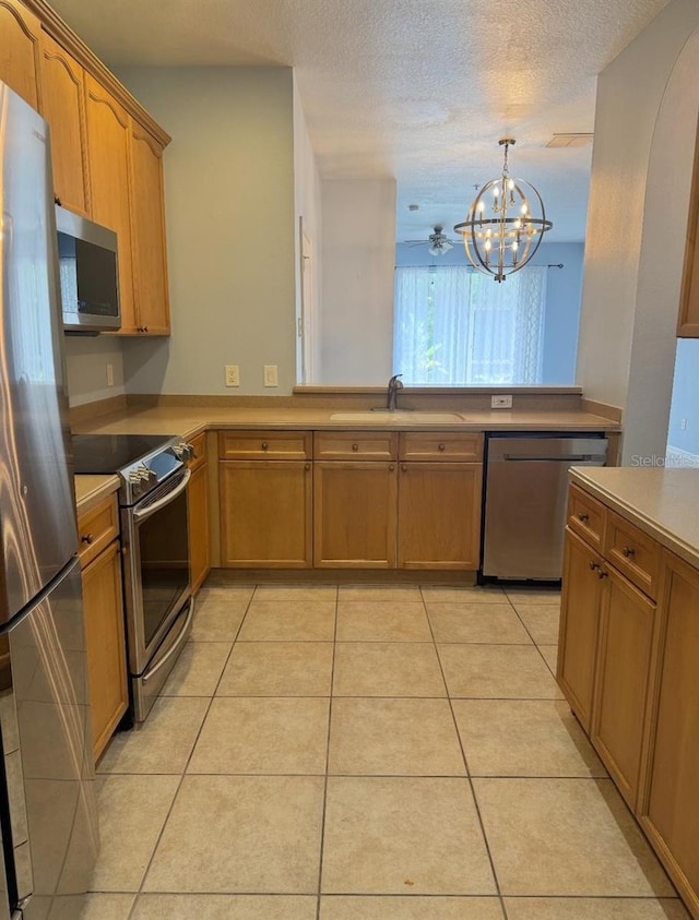 kitchen with decorative light fixtures, appliances with stainless steel finishes, a sink, light tile patterned floors, and a notable chandelier