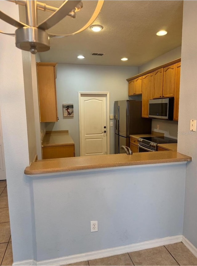 kitchen with brown cabinetry, stainless steel appliances, recessed lighting, light tile patterned floors, and visible vents