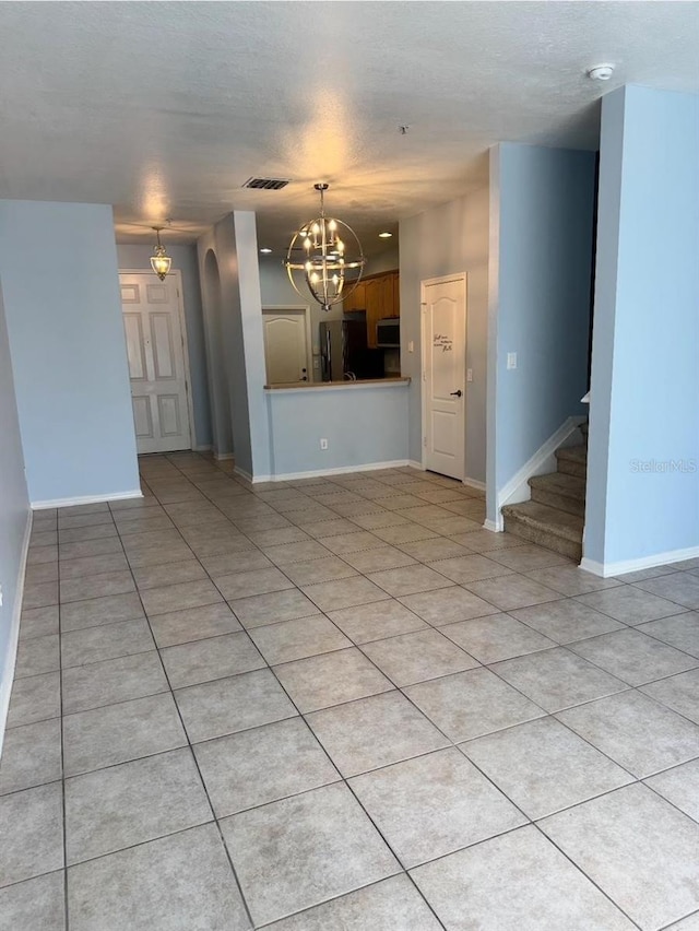 unfurnished living room featuring visible vents, stairs, light tile patterned flooring, baseboards, and a notable chandelier