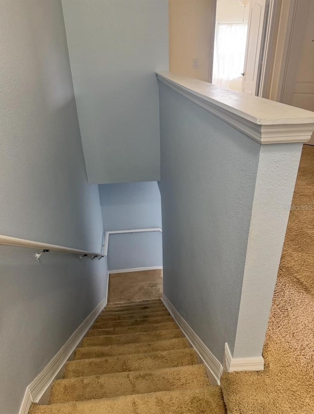 stairway with carpet flooring, baseboards, and a textured wall