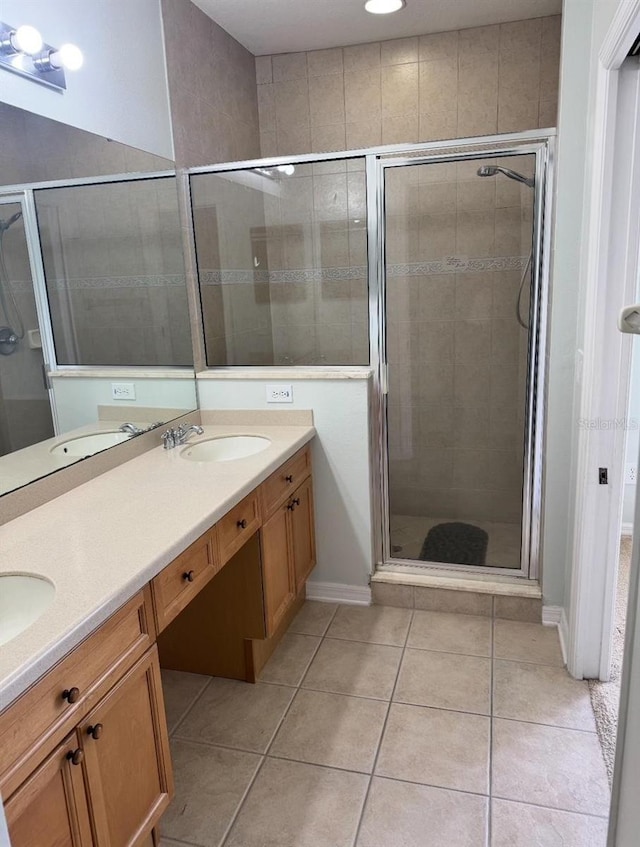bathroom featuring double vanity, a sink, tile patterned flooring, and a stall shower
