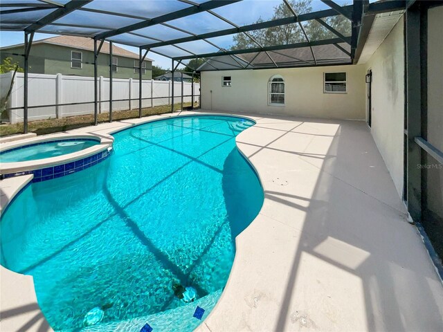 view of pool with fence, a patio area, glass enclosure, and a pool with connected hot tub