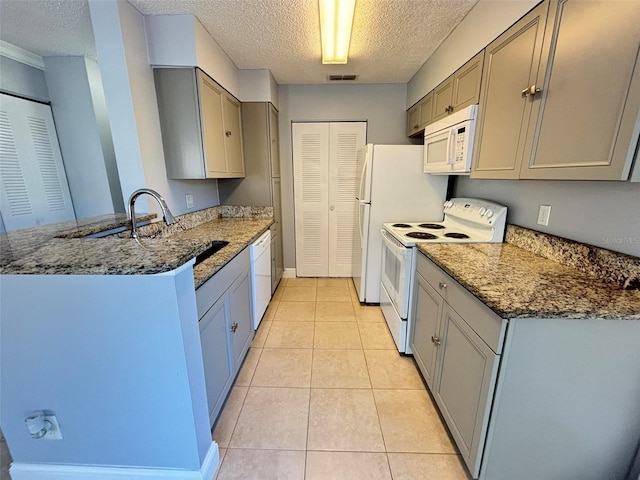 kitchen with visible vents, white appliances, a peninsula, a textured ceiling, and gray cabinets