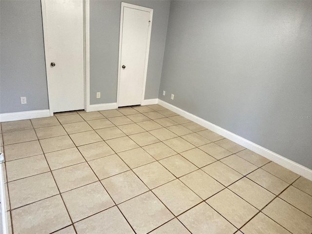 spare room featuring light tile patterned floors and baseboards