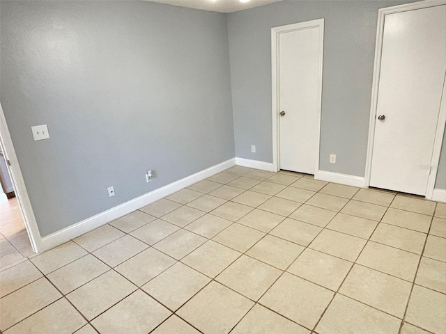 unfurnished bedroom with light tile patterned floors and baseboards