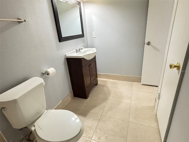 bathroom featuring toilet, tile patterned floors, vanity, and baseboards