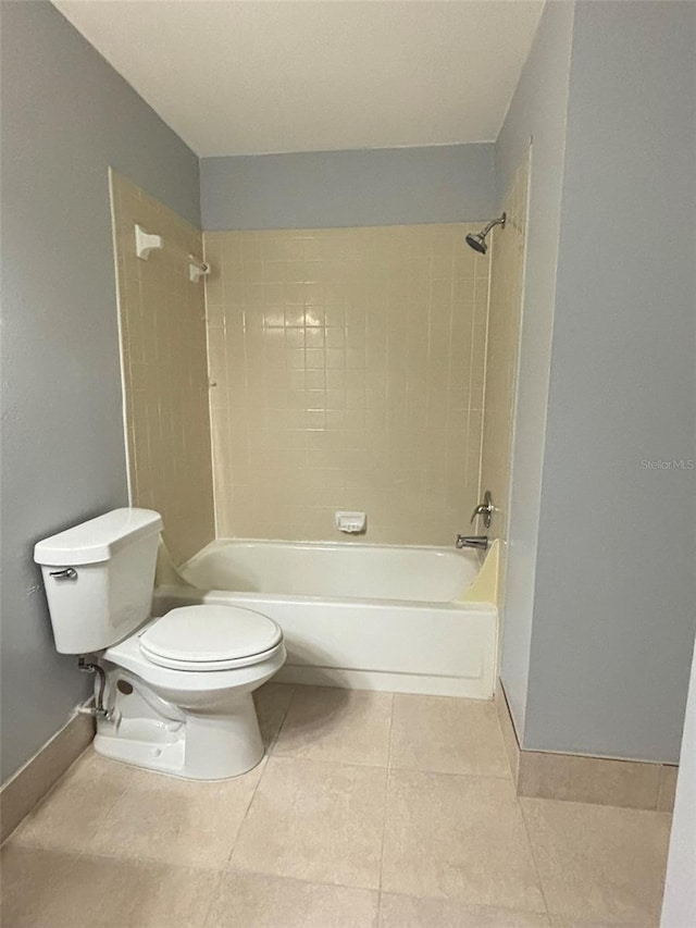 bathroom featuring toilet, tile patterned floors, baseboards, and shower / bathtub combination