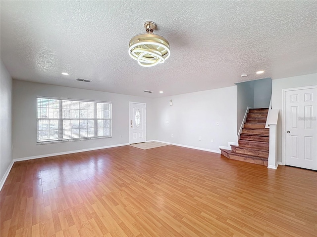 1176 Liberty Hall Dr, Kissimmee, FL 34746 - unfurnished living room featuring a textured ceiling, light wood-style floors, baseboards, stairs, and recessed lighting