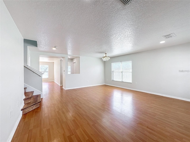 1176 Liberty Hall Dr, Kissimmee, FL 34746 - unfurnished living room featuring wood finished floors, a textured ceiling, stairway, and baseboards