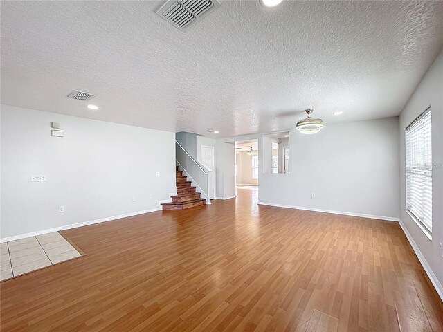 1176 Liberty Hall Dr, Kissimmee, FL 34746 - unfurnished living room featuring wood finished floors, a textured ceiling, baseboards, stairs, and recessed lighting