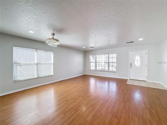 1176 Liberty Hall Dr, Kissimmee, FL 34746 - unfurnished living room featuring a textured ceiling, baseboards, wood finished floors, recessed lighting, and a chandelier