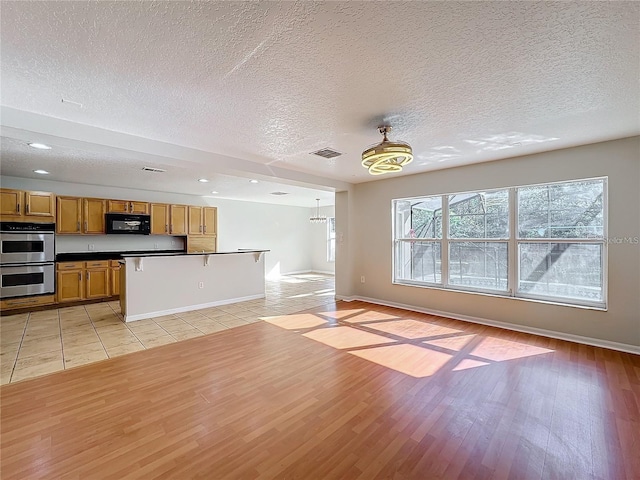 1176 Liberty Hall Dr, Kissimmee, FL 34746 - unfurnished living room with a textured ceiling, light wood-type flooring, baseboards, and recessed lighting