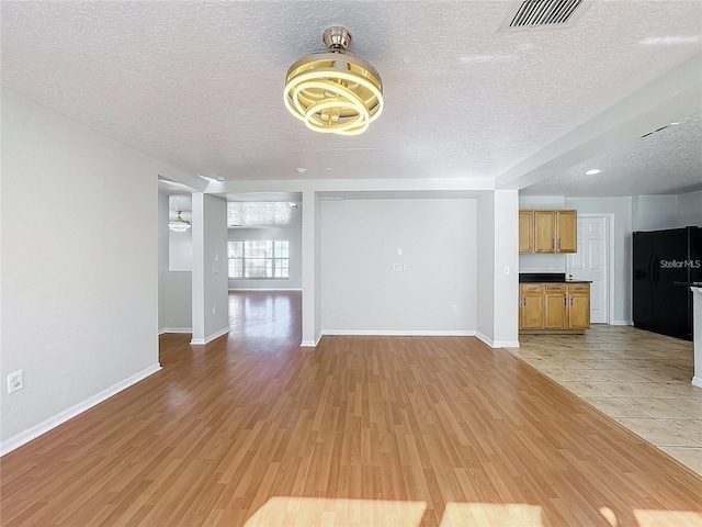 1176 Liberty Hall Dr, Kissimmee, FL 34746 - unfurnished living room with a textured ceiling, light wood-type flooring, and baseboards